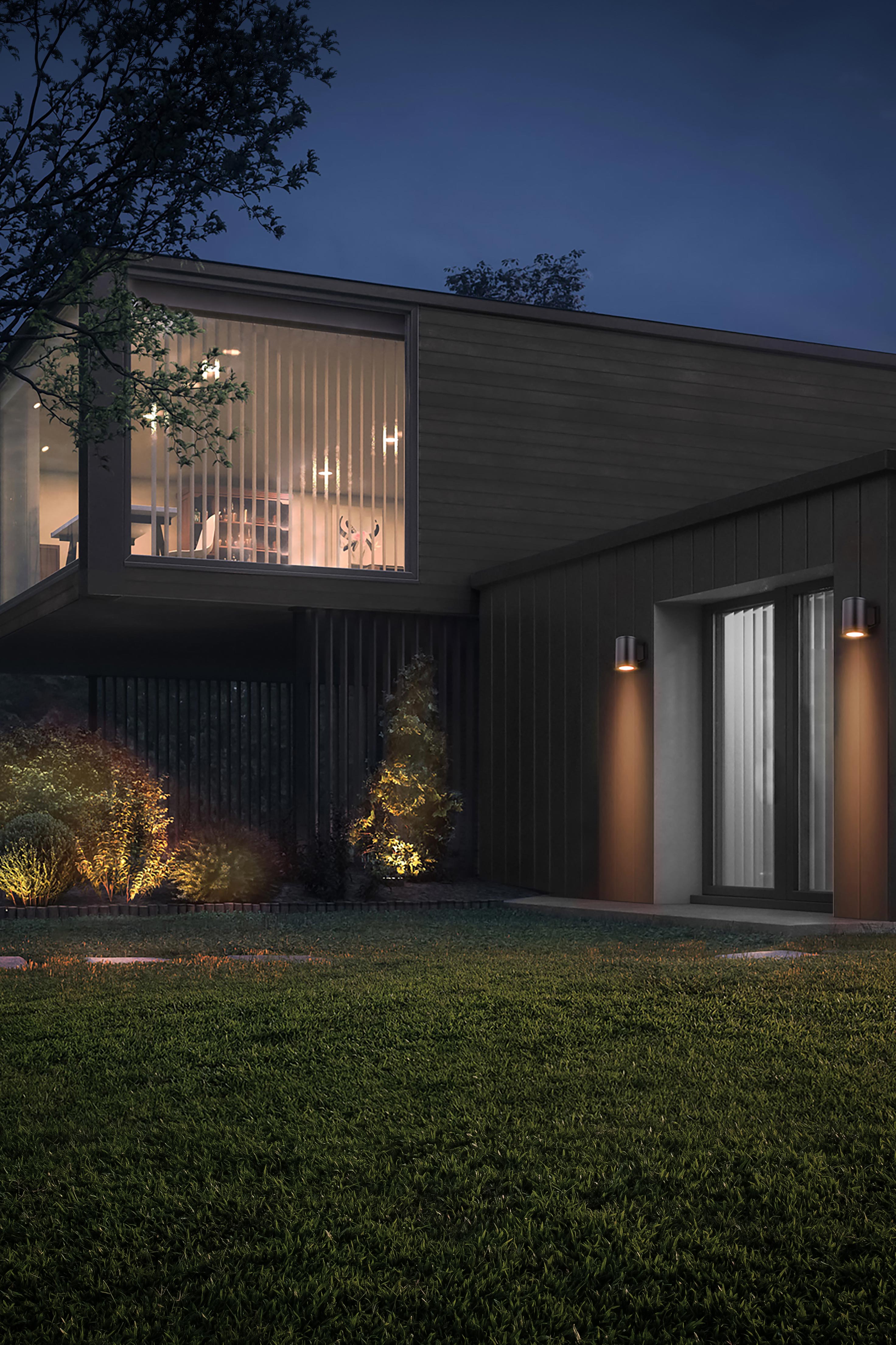 Exterior view of a modern house at night with warm landscape uplighting