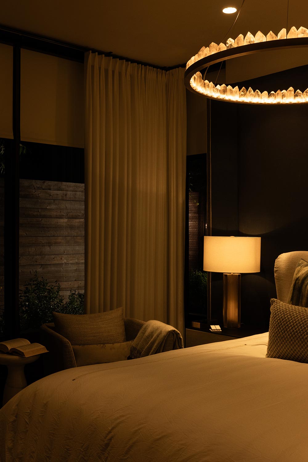 Dimly lit bedroom featuring a crystal ring chandelier and bedside lamp