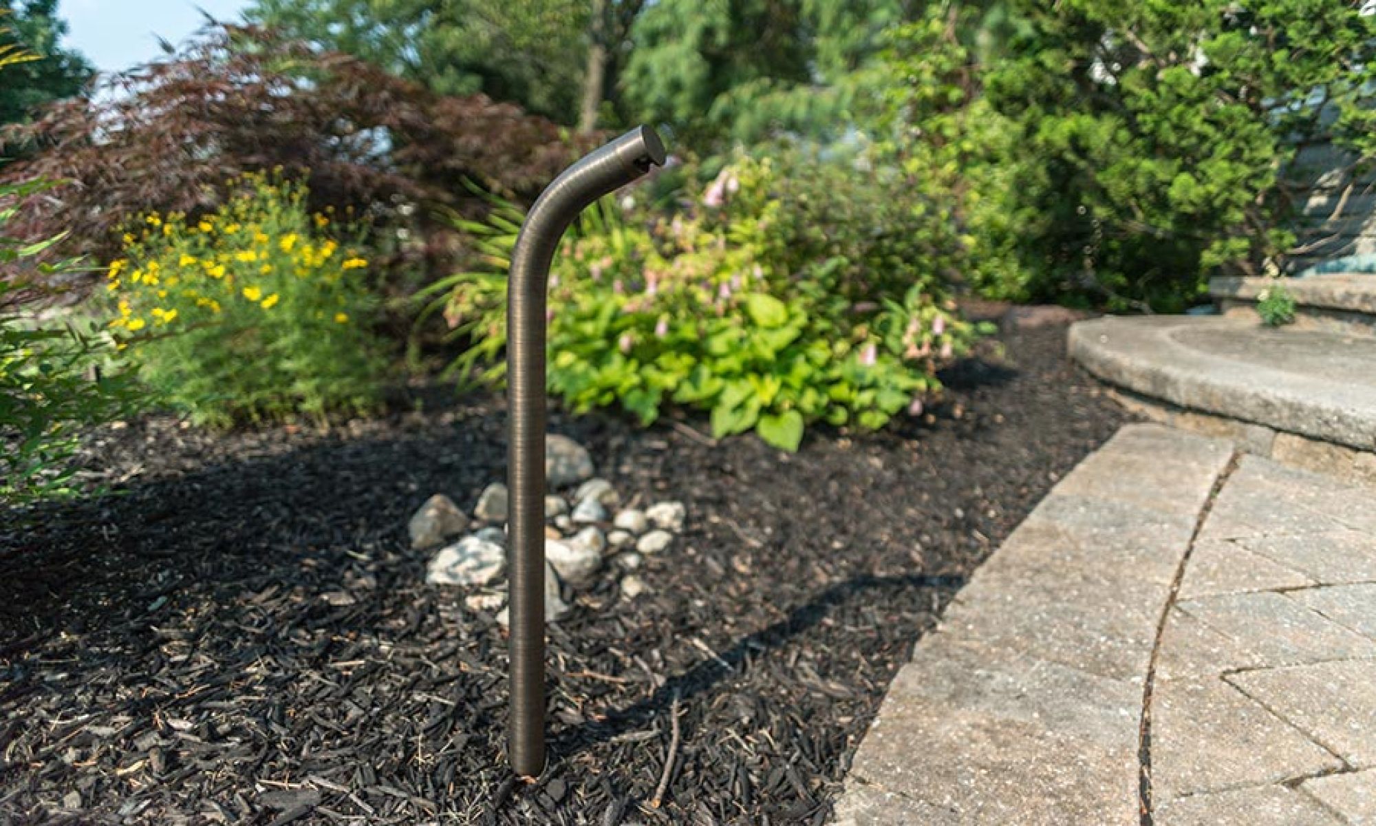 Sleek bronze path light installed in a garden mulch bed