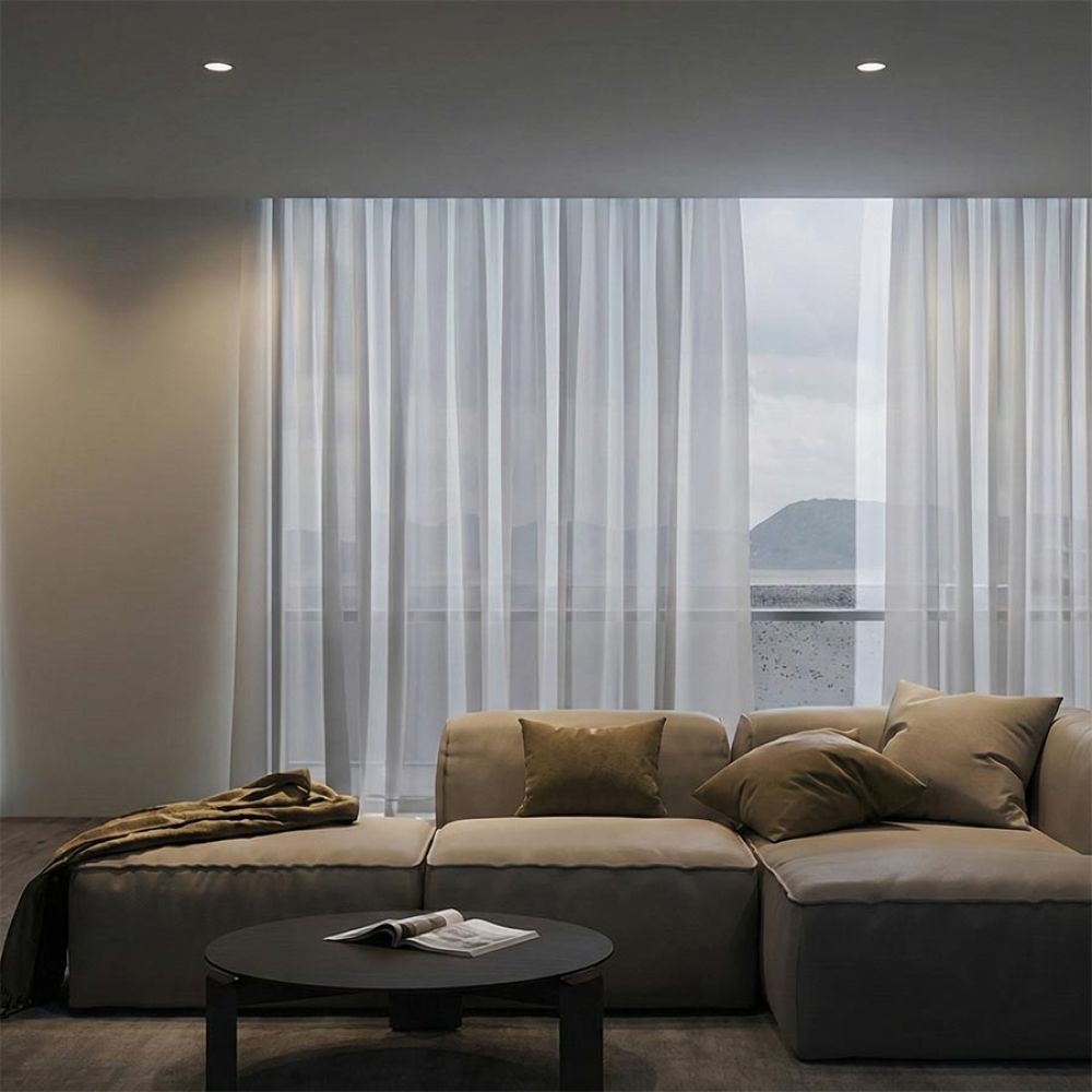 Contemporary living room with a low-profile sectional sofa and sheer white curtains