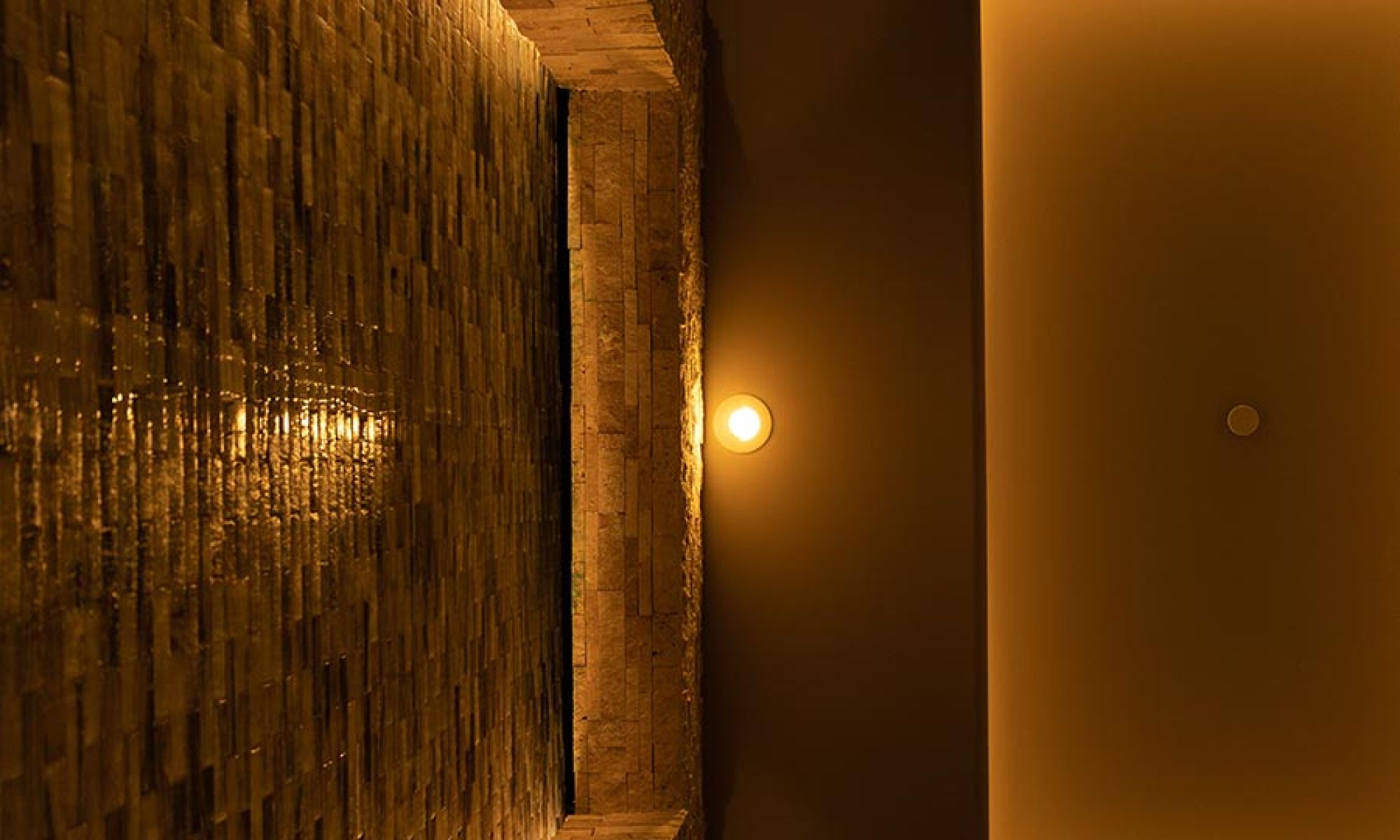 Warm circular light illuminating a stone brick wall and smooth ceiling panels